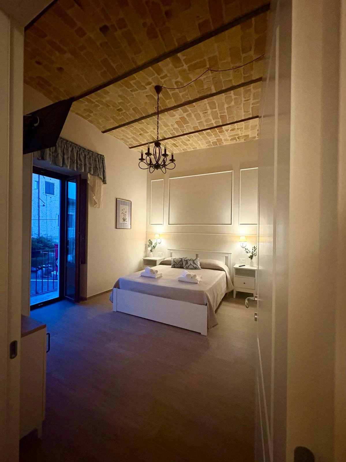 La camera matrimoniale al calar della sera, con il soffitto a volta in mattoni e il balcone affacciato sulla strada