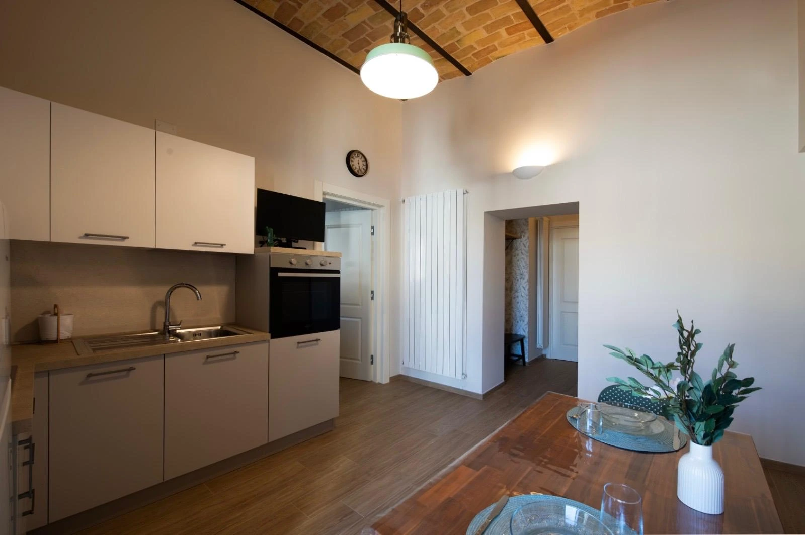 La cucina della Dimora vista dal tavolo da pranzo, con il corridoio verso le camere