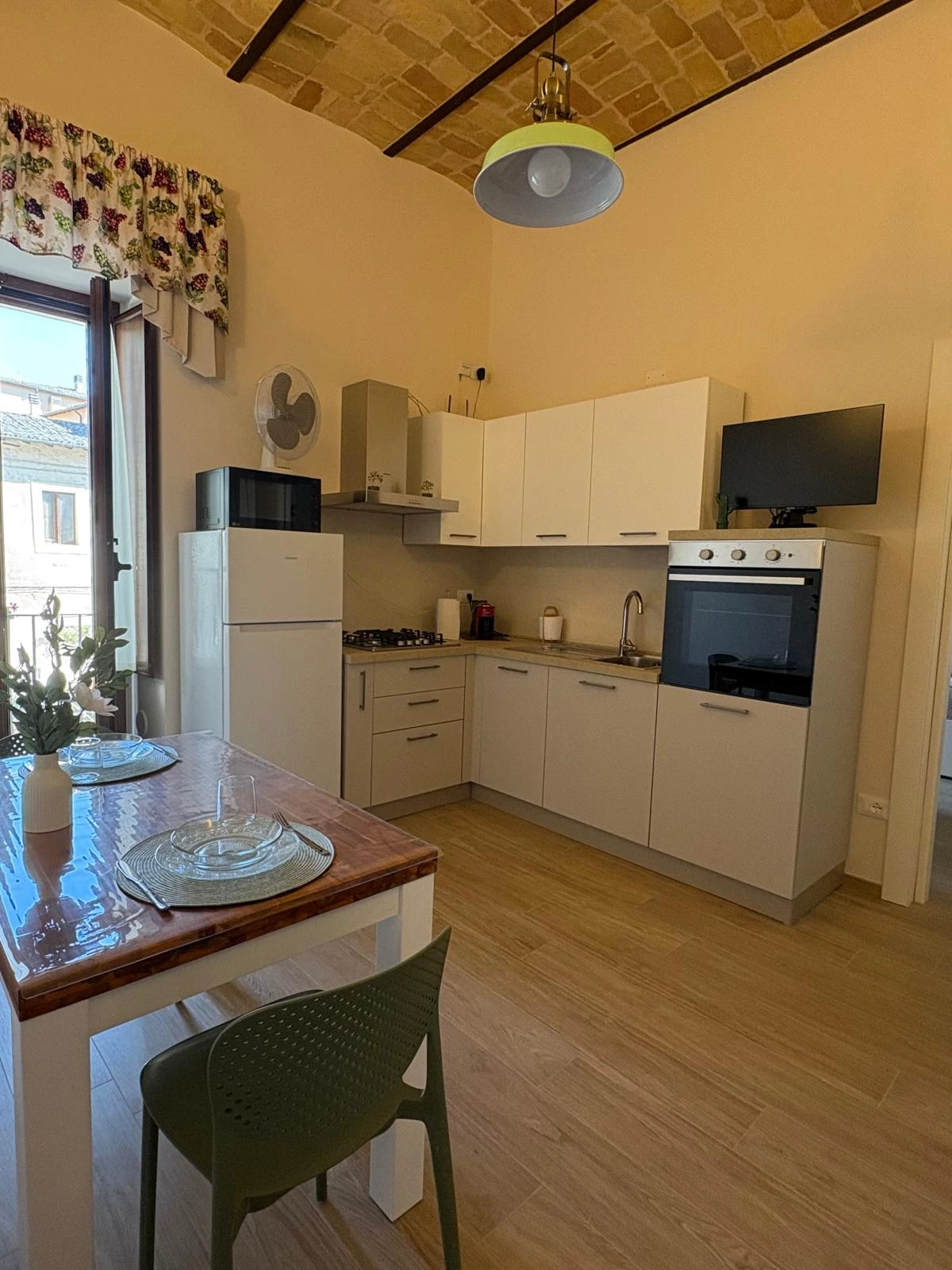 La cucina della Dimora con il tavolo apparecchiato, sotto il soffitto a volta in mattoni